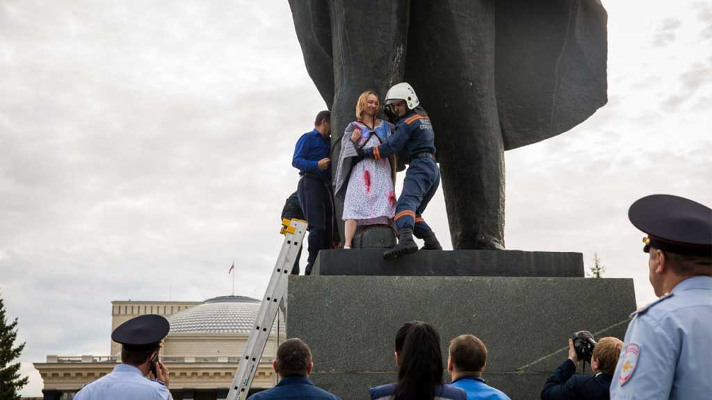 Новый День: &#39;&#39;Против нищеты и полицейского государства&#39;&#39;: девушка с флагом России приковала себя к памятнику Ленину в Новосибирске